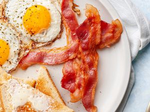 Plate of Microwave Bacon with Sunny Side Eggs and Slices of Buttered Toast