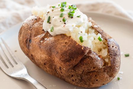 Baked potato topped with sour cream, pepper, and chives