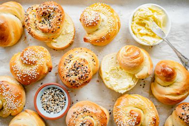 Challah Rolls on a Tray with Some Cut in Half and Smeared with Butter