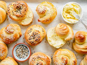 Challah Rolls on a Tray with Some Cut in Half and Smeared with Butter