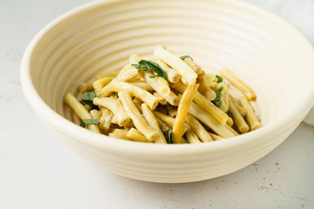 Side view of yellow beans in a cream colored bowl.