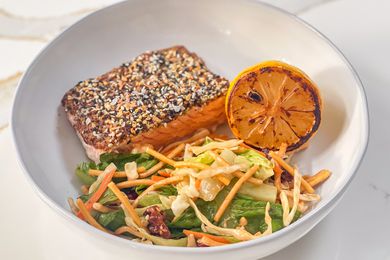 3-ingredient everything bagel salmon served with a charred lemon half and a side salad, all in a white bowl