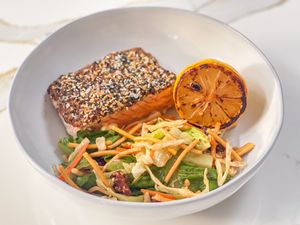 3-ingredient everything bagel salmon served with a charred lemon half and a side salad, all in a white bowl