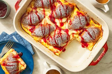 Monte Cristo croissant casserole in a casserole dish and in the surroundings, a serving on a small plate with a fork, a container of jelly, and cups of coffee