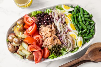 A platter with a Nicoise salad ready to be dressed and served