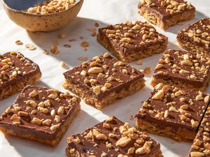 Oh Henry bars on a crinkled parchment paper with a bowl of crushed peanuts 