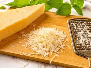 A block of cheese grated on a cutting board