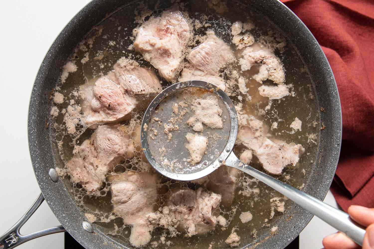 Fat Skimmer Used to Remove Scum from Pot of Boiling Pork for Asado de Carajay Recipe