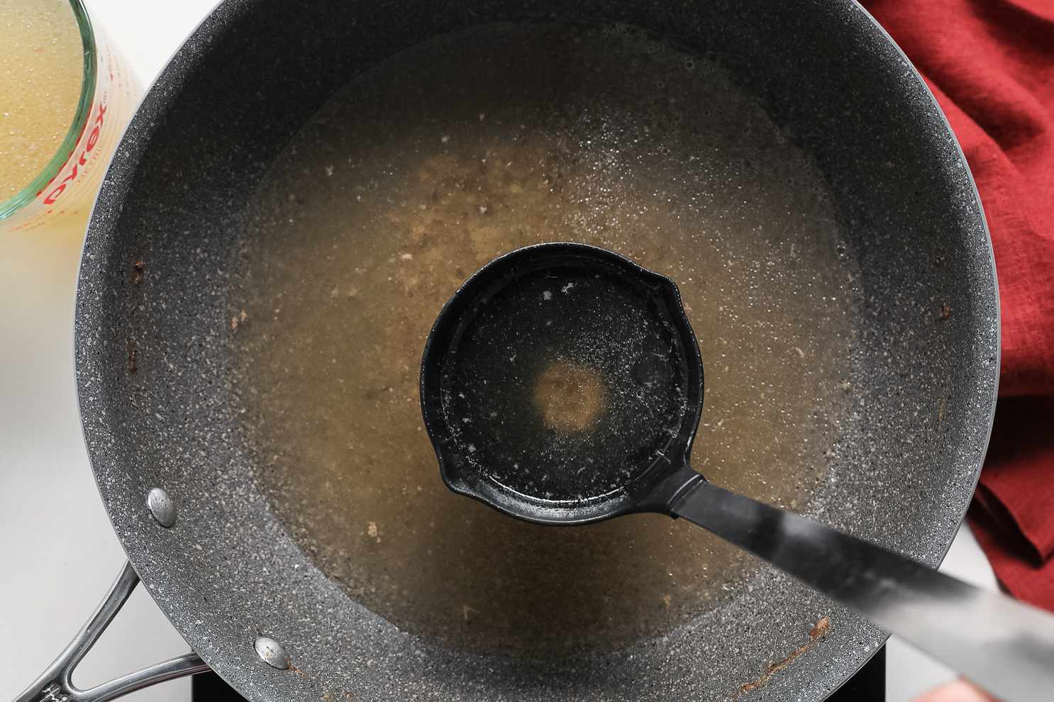 Ladle Used to Move Two Cups Worth of Pork Broth from Pot to Measuring Cup for Pork Asado de Carajay