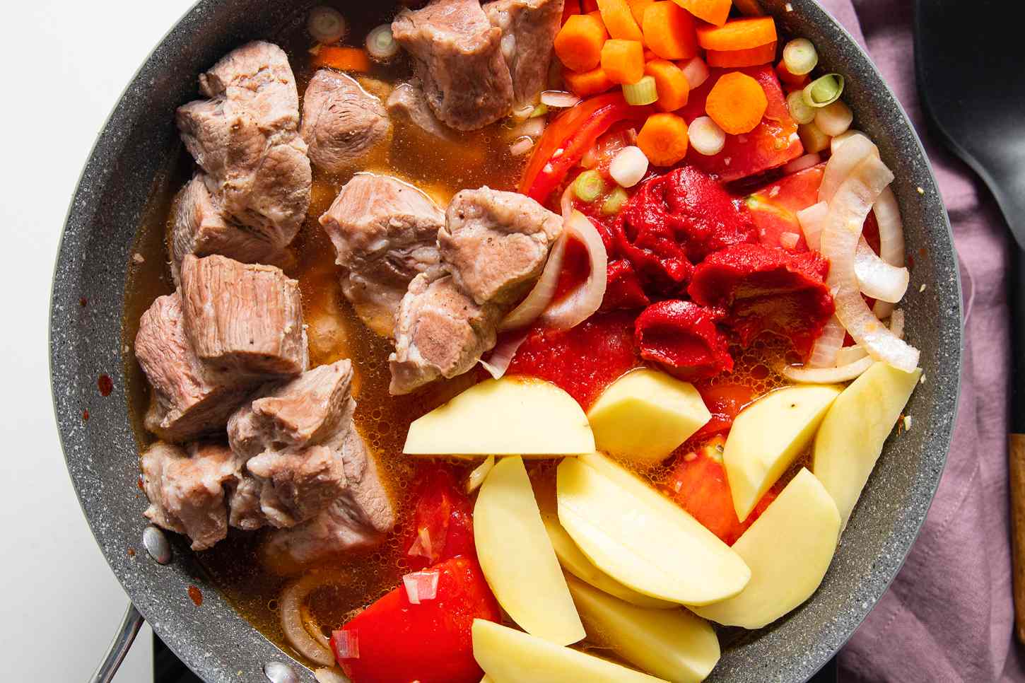 Boiled Pork, Carrots, Tomato Paste, and Potatoes Added to Pot With Onions and Tomatoes for Pork Asado de Carajay Recipe