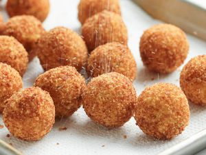 Potato Croquettes Sprinkled with Salt, All Sitting on a Paper Towel Lined Baking Pan