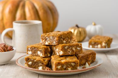 Pile of Pumpkin Blondies on a Plate with Fall Decor in the Background