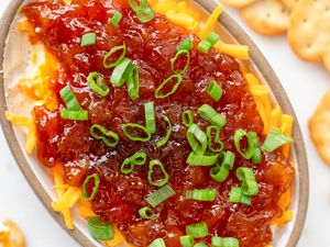 A dish of chutney cheese appetizer dip with crackers in the background