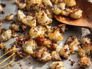 Photo of roasted cauliflower on a sheet pan with yellow-lined illustrations on the corner
