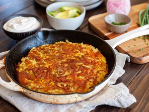 Slice of Rosti on a Plate with Bacon, Sour Cream, Sliced Avocados, and Sliced Onions