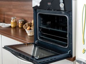 Photo of an open oven with an exclamation illustration next to it