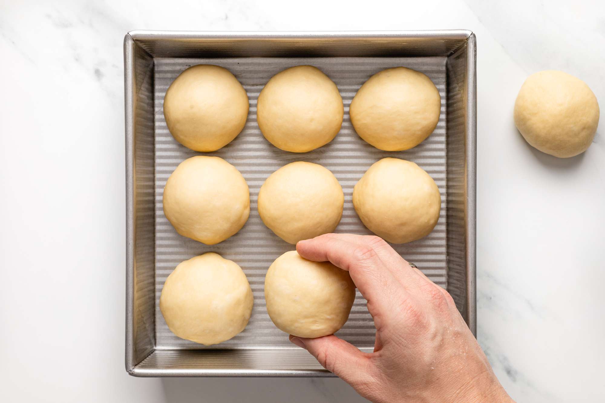 dinner rolls being placed in a cake pan