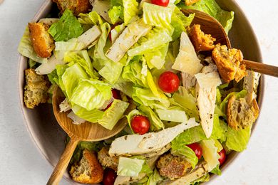 Two salad spoons used to mix sheet pan caesar salad