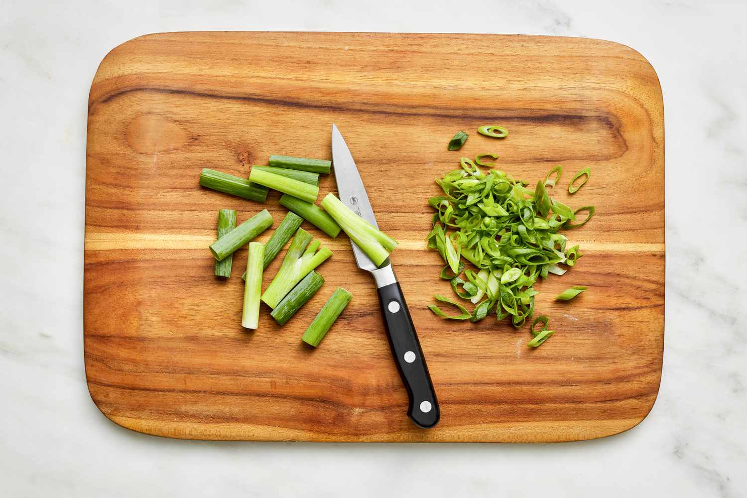 Green onions on a cutting board (half thinly sliced, half cut into 1 1/2-inch pieces) for 5-ingredient sheet pan salmon recipe