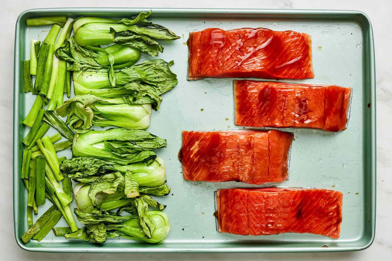 Teriyaki glazed salmon added to sheet pan (vegetables are pushed to one side of the pan) for sheet pan salmon recipe