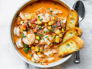 Bowl of Shrimp and Chorizo Chowder Topped with Parsley and Slices of Toasted Baguette