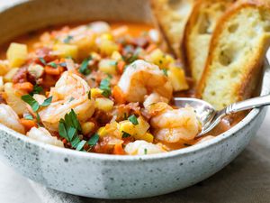 Bowl of Shrimp and Chorizo Chowder Topped with Parsley and Slices of Toasted Baguette