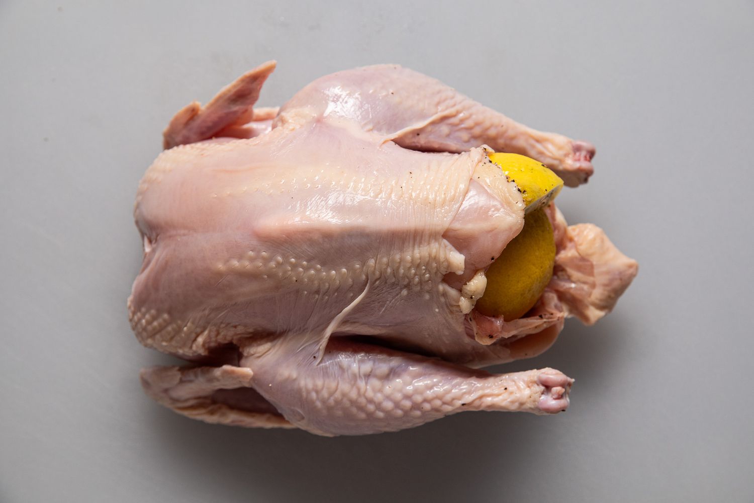 Whole chicken stuffed with halved lemon slices for simple roast chicken recipe