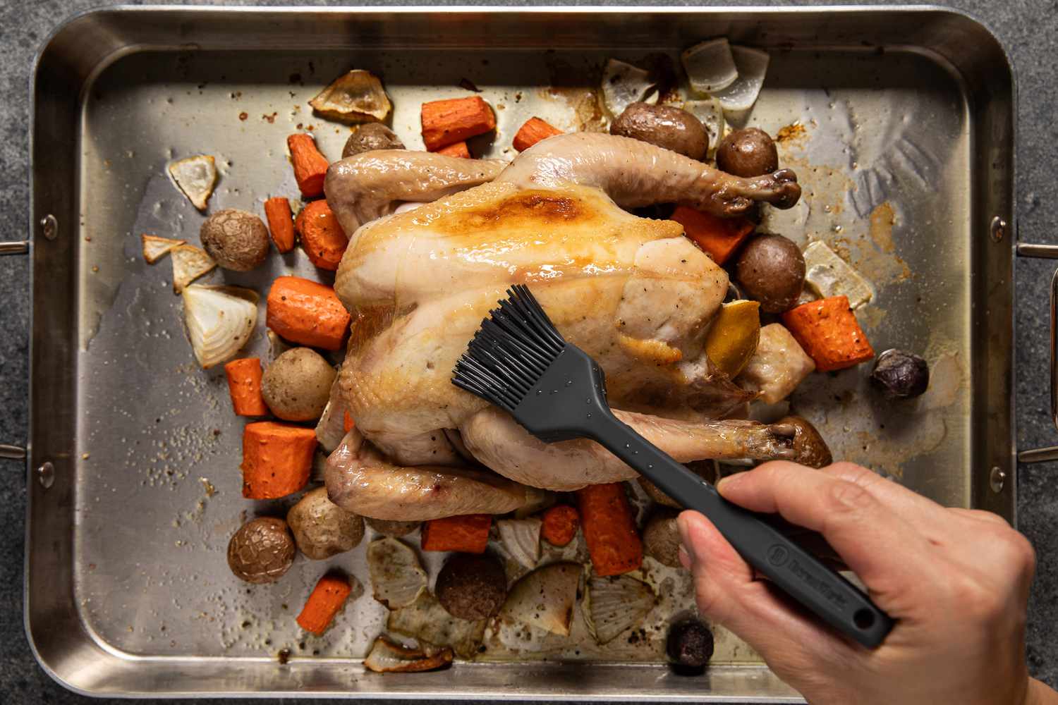 Silicone basting brush used to baste roasted chicken with pan juices