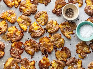 Smashed Potatoes and Two Small Bowls (One with Cracked Pepper and Another with Flaky Salt) on a Baking Pan 