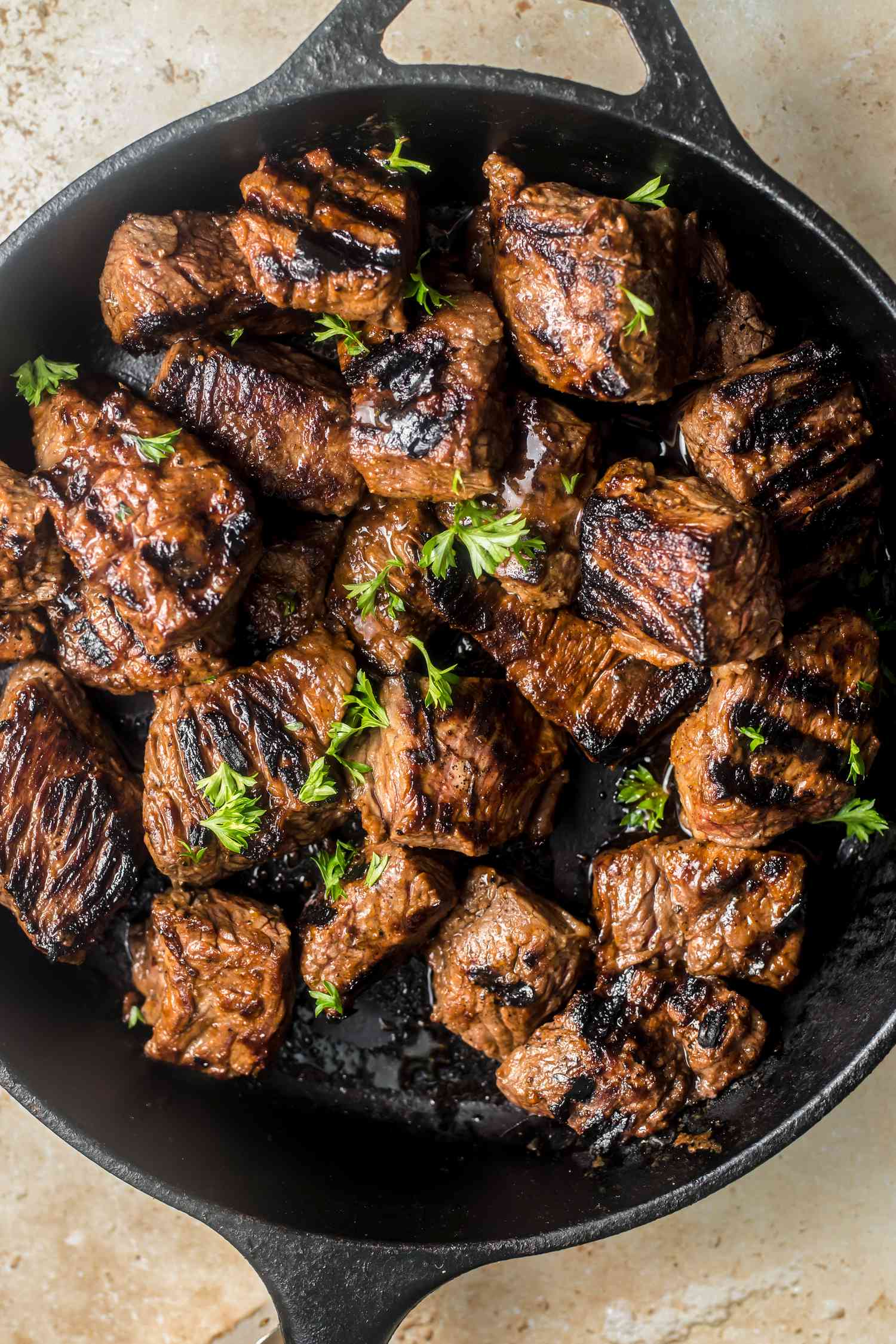 Steak tips topped with parsley on a cast iron skillet