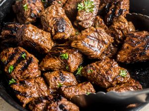 Close-up: steak tips topped with parsley on a cast iron skillet