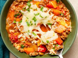 Bowl of stuffed pepper soup topped with cheese and some of the soup in a spoon being taken from the bowl