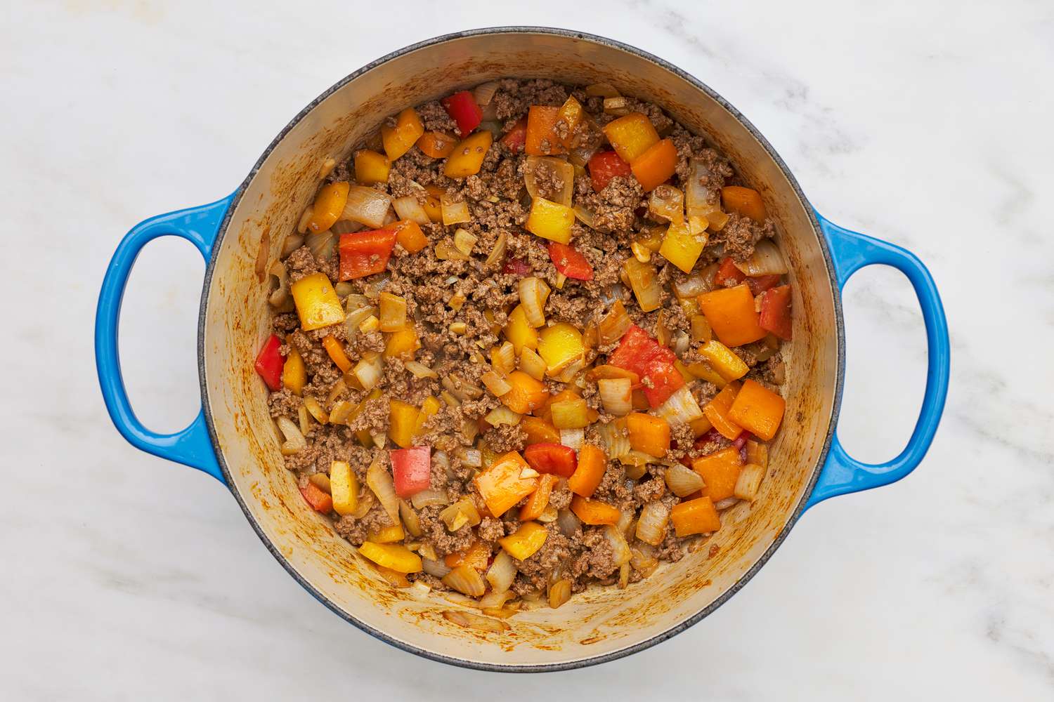 Cooked browned beef and sauteed vegetables in a dutch oven for stuffed pepper soup recipe