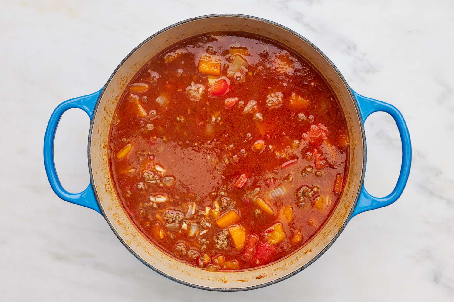 Crushed canned tomatoes and beef broth added to dutch overn for stuffed pepper soup recipe