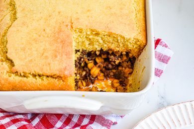 A casserole dish with a tamale pie and a piece missing.