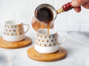 Turkish Coffee Poured into a Cup on a Coaster from a Cezve 