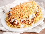 Vegan Cincinnati Chili Served over a Platter of Pasta and Topped with Cheese and Onions