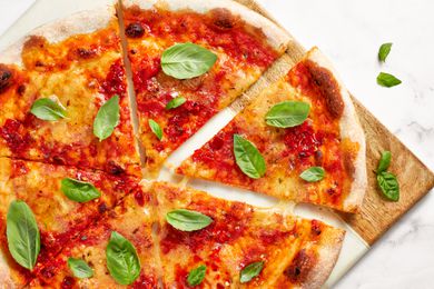 Vegan Pizza Cut Into Slices and Topped With Fresh Basil on a Cutting Board