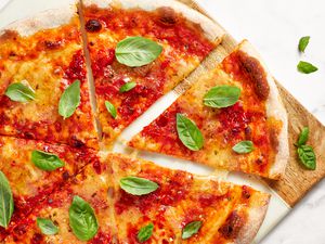 Vegan Pizza Cut Into Slices and Topped With Fresh Basil on a Cutting Board