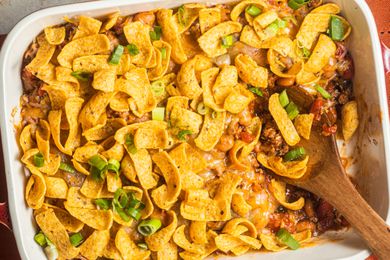 Walking taco casserole in a casserole dish with a spoon (casserole dish missing some casserole / some of the casserole was already served)