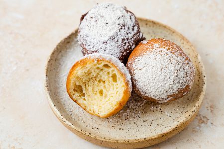 A Small Plate with Three Zeppole, One Is Missing a Bite 