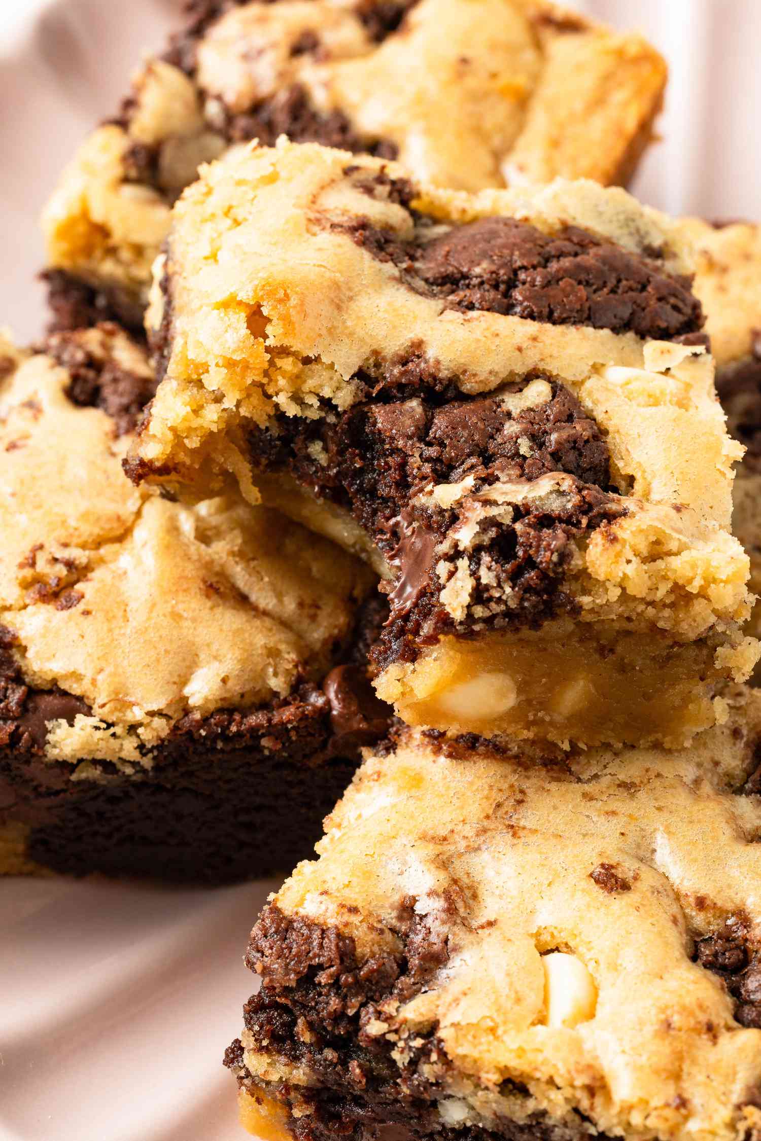 Close-up of a slice of marble brownie missing a bite surrounded by more, unbitten slices, all on a plate 