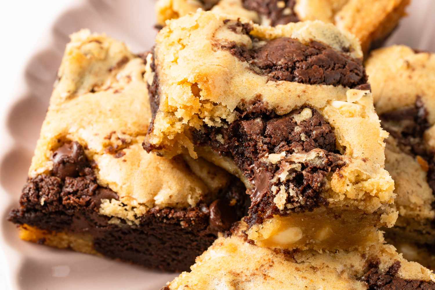 Close-up of a slice of marble brownie missing a bite surrounded by more, unbitten slices, all on a plate 