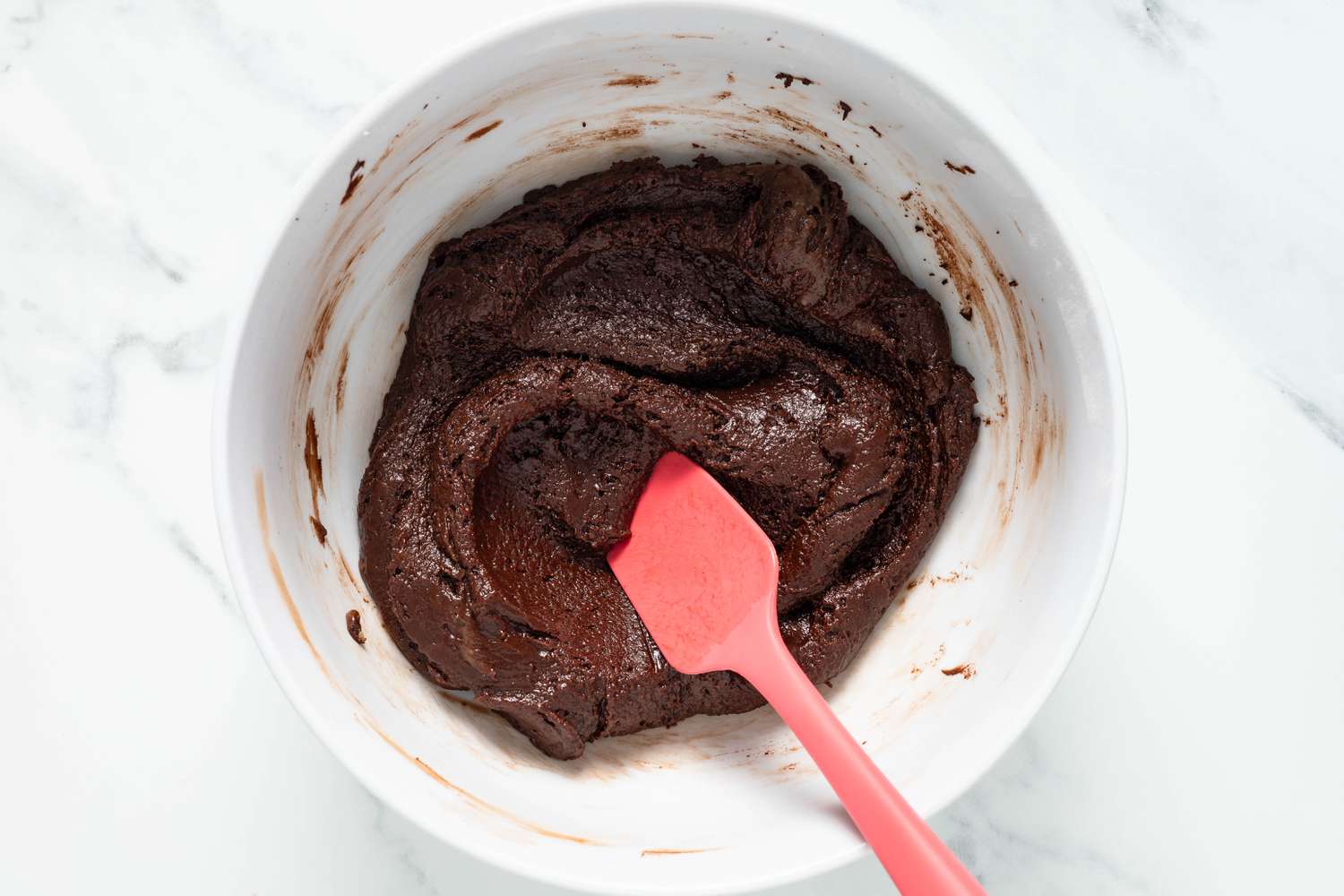 Brownie batter mixed together in a bowl using a rubber spatula