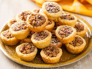 Stack of pecan pie cookies on a plate with a mustard colored table napkin in the background