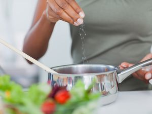 person adding a pinch of salt to pot