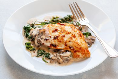 Chicken Florentine on white plate with fork.